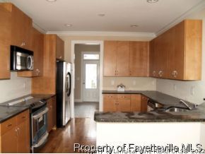 Lot 279 Falling Water Road Spring Lake, NC 28390 - Photo 3 of 12 a kitchen with a sink a refrigerator and wooden cabinets