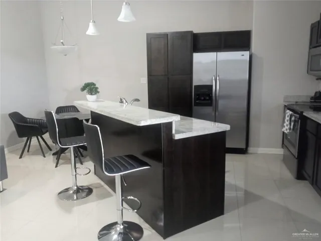 a kitchen with a sink a refrigerator and chairs
