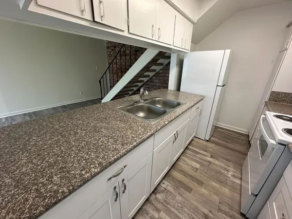 a kitchen with granite countertop sink stove and cabinets