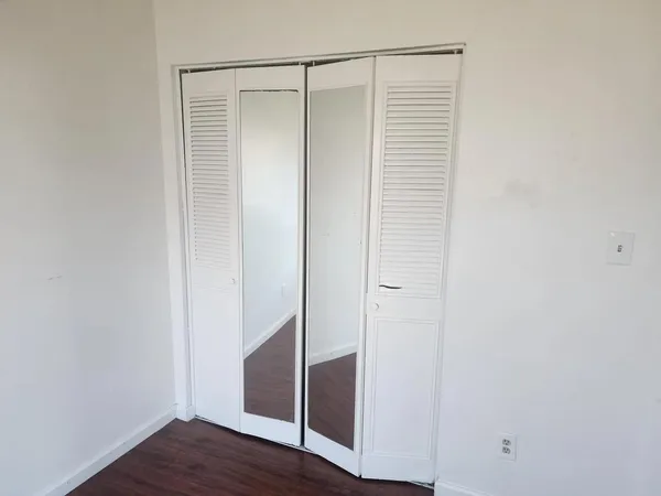 an empty room with wooden floor cabinet and windows