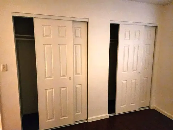 an empty room with wooden floor closet and windows