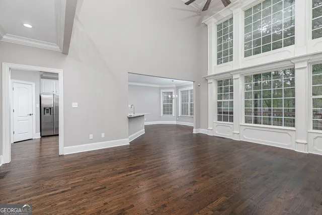 an empty room with wooden floor fireplace and windows