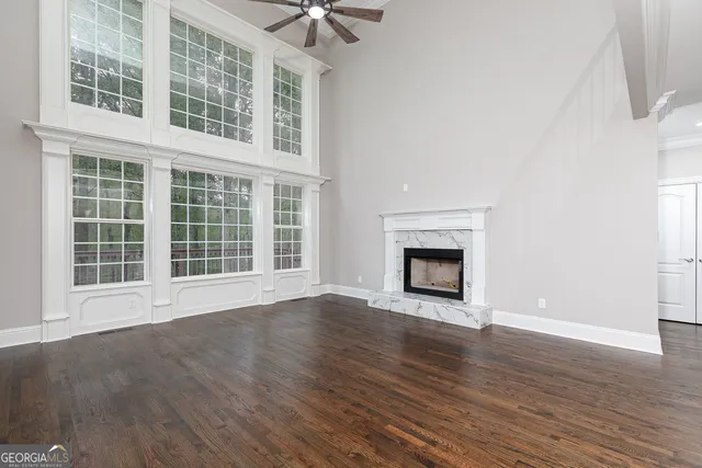 a view of an empty room with wooden floor fireplace and a window