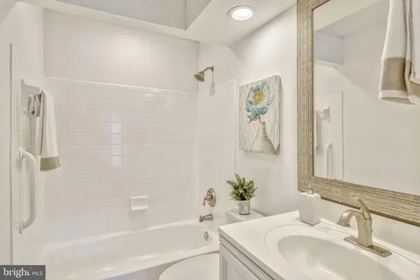 a bathroom with a granite countertop sink a mirror a bathtub and shower