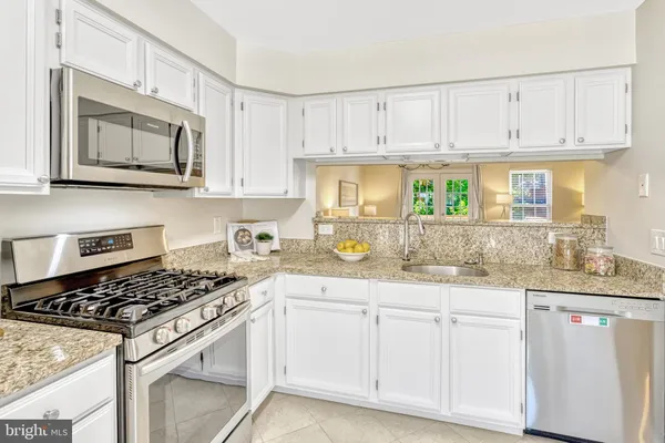 a kitchen with granite countertop a sink a stove and cabinets