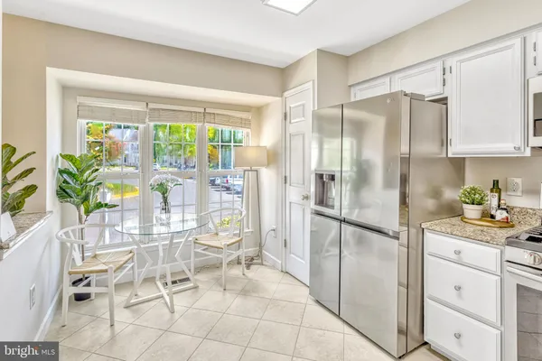 a kitchen with granite countertop a refrigerator a stove a dining table and chairs