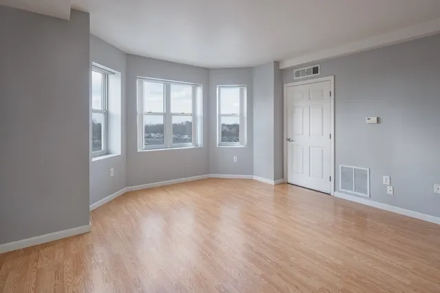 a view of an empty room with wooden floor and a window