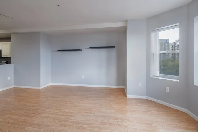 a view of an empty room with window and wooden floor