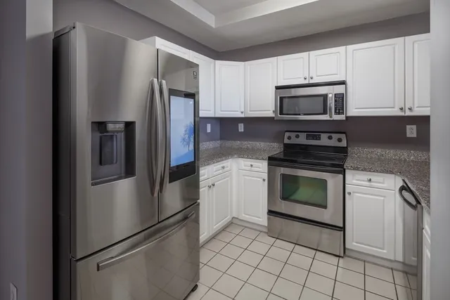 a kitchen with stainless steel appliances white cabinets white stove a refrigerator and a microwave