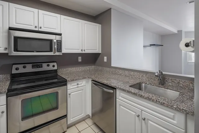 a kitchen with granite countertop a sink stove and microwave
