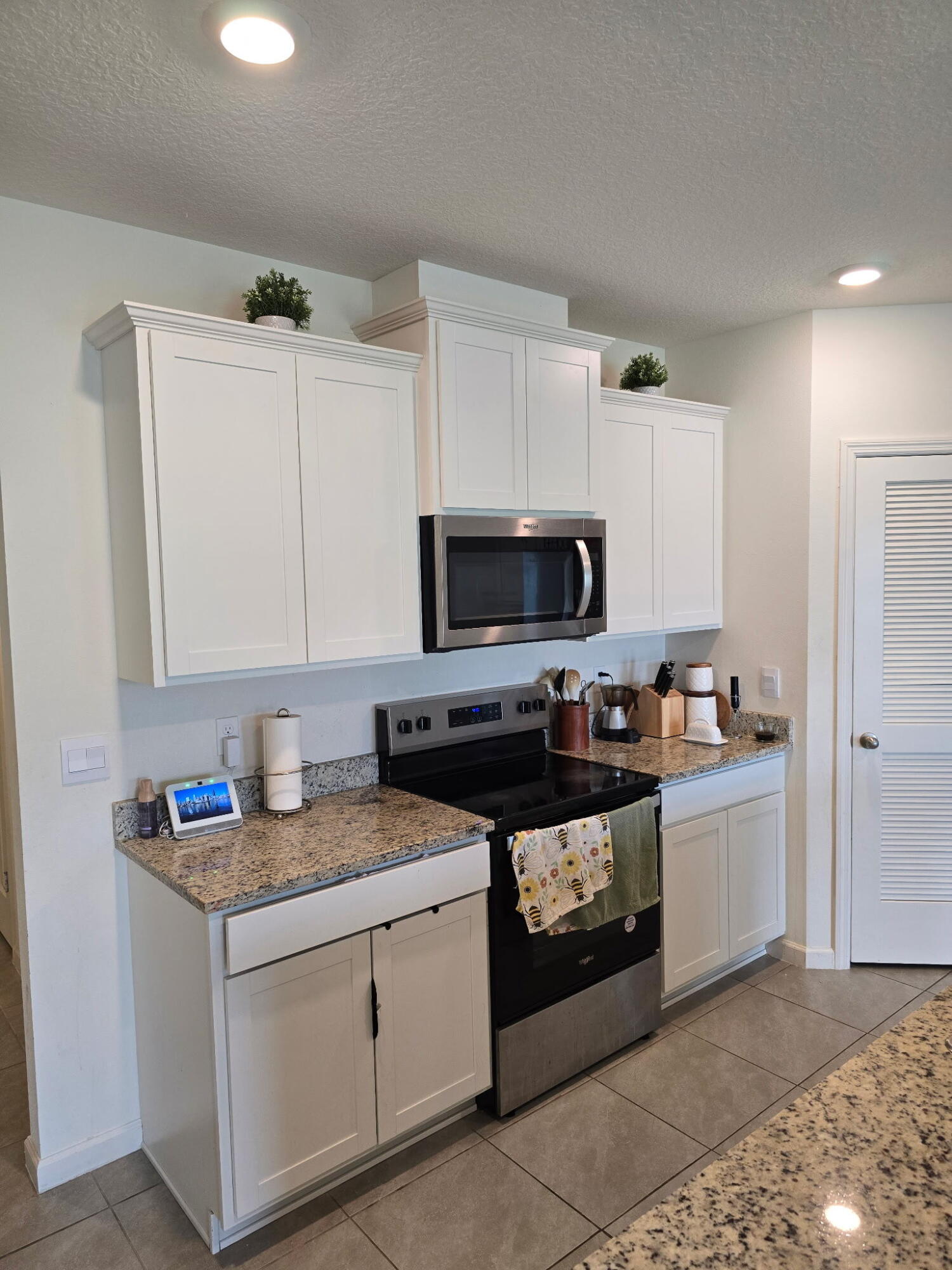 9725 Southwest Triton Way Port Port St. Lucie, FL 34987 - Photo 3 of 12 a kitchen with granite countertop a sink dishwasher stove and white cabinets