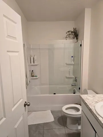 a bathroom with a granite countertop sink toilet and shower