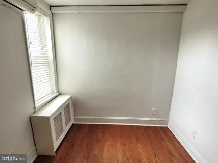 a view of an empty room with hardwood and a window