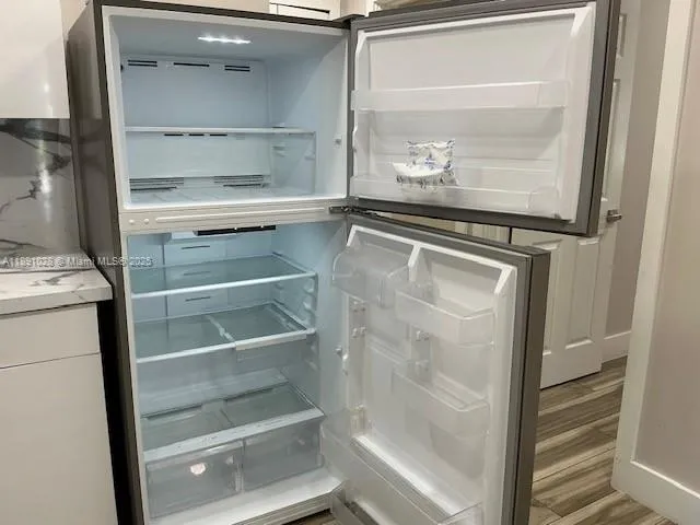 a view of a refrigerator in kitchen and white cabinets
