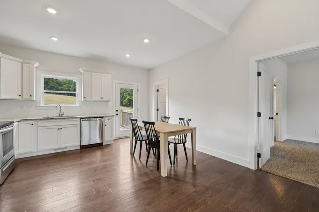 a kitchen with stainless steel appliances granite countertop a table chairs sink and cabinets