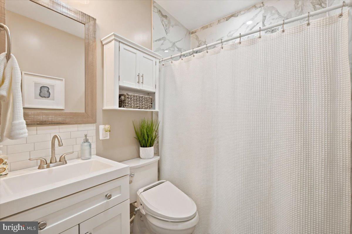 2800 South Arlington Ridge Road Arlington, VA 22206 - Photo 25 of 54 a bathroom with a sink a toilet a mirror and shower curtain