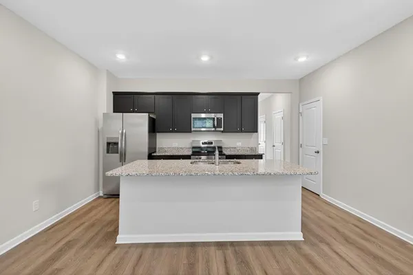 a view of a kitchen with stainless steel appliances granite countertop a stove a sink and a refrigerator