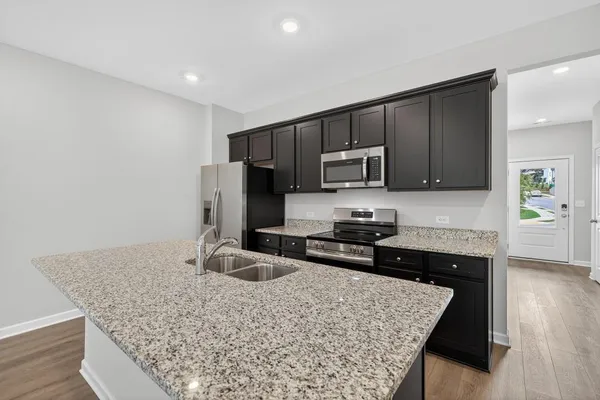 a kitchen with stainless steel appliances granite countertop a stove top oven a sink and dishwasher a refrigerator with wooden floor