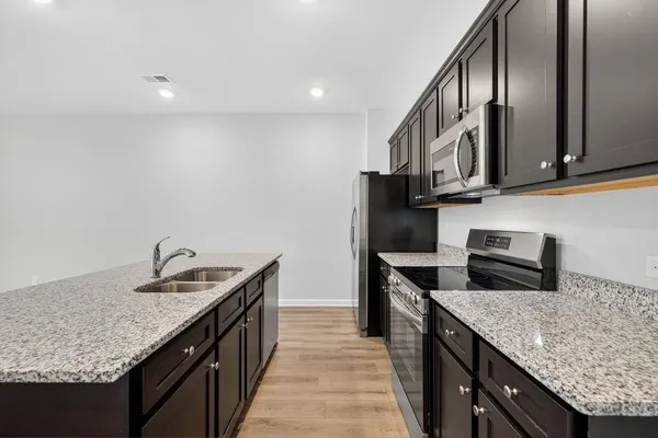 a kitchen with stainless steel appliances granite countertop a sink a stove and a refrigerator