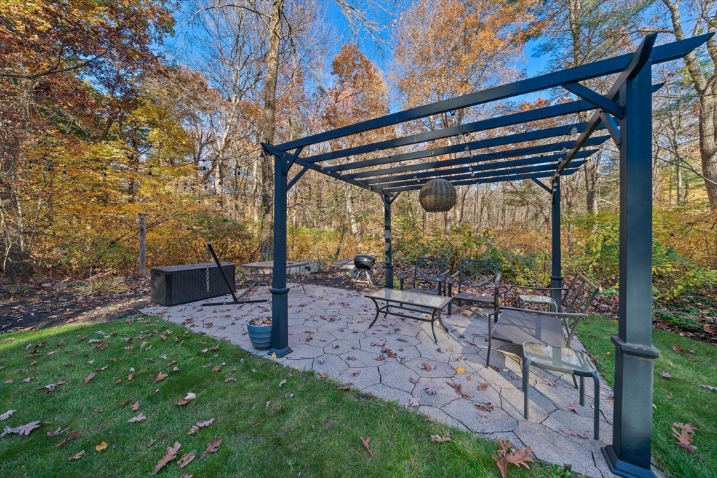 24 Pammys Path Easton, MA 02356 - Photo 34 of 39 a view of a patio with table and chairs under an umbrella with a large tree