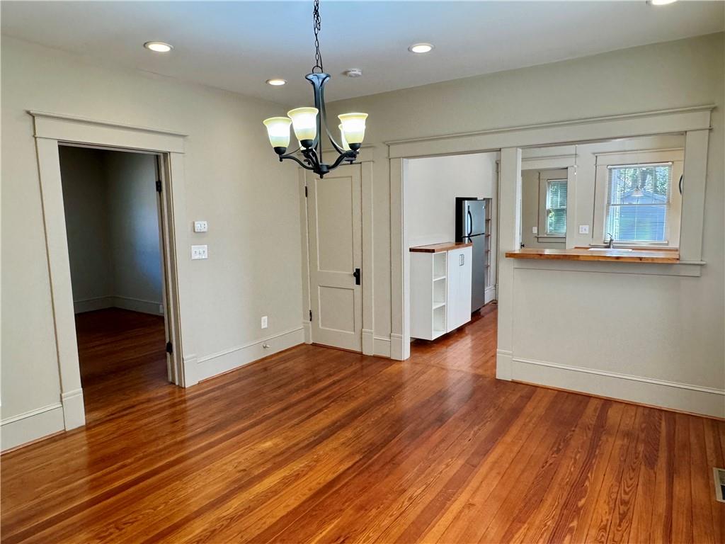 2482 Maple Street East Point, GA 30344 - Photo 12 of 39 an empty room with wooden floor chandelier and kitchen view