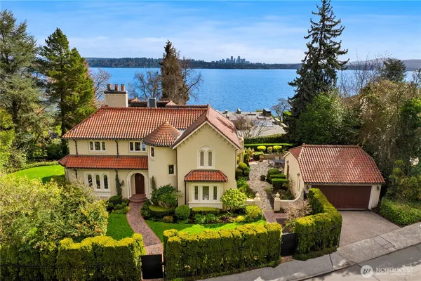 a front view of a house with a garden and lake view
