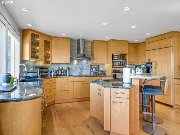 a kitchen with stainless steel appliances granite countertop a refrigerator a stove top oven and a sink with couches