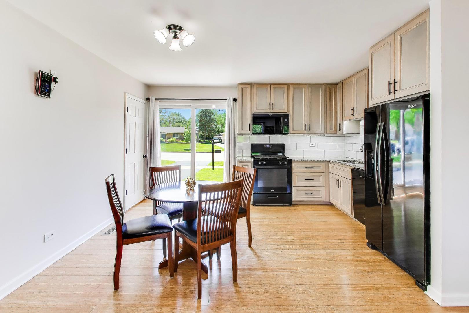 420 Bode Road Hoffman Estates, IL 60169 - Photo 6 of 20 a kitchen with stainless steel appliances a dining table chairs refrigerator and sink