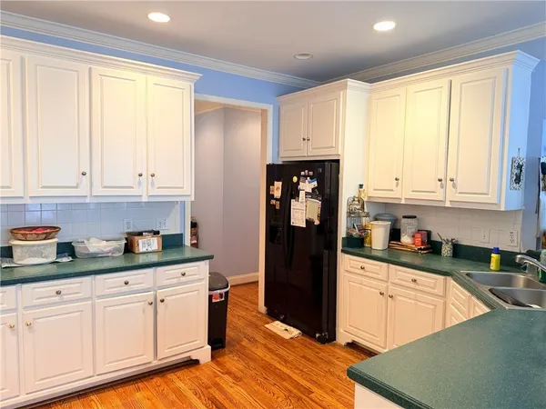 a kitchen with granite countertop a refrigerator a sink and white cabinets
