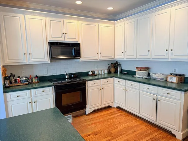 a kitchen with stainless steel appliances granite countertop a stove a sink and white cabinets