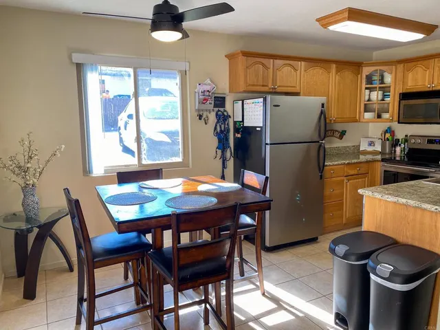 a kitchen with stainless steel appliances kitchen island a table chairs and a refrigerator