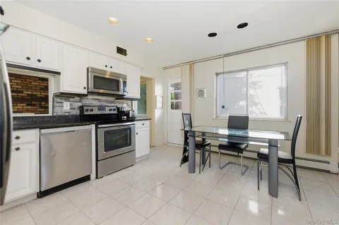 a kitchen with stainless steel appliances white cabinets and chairs
