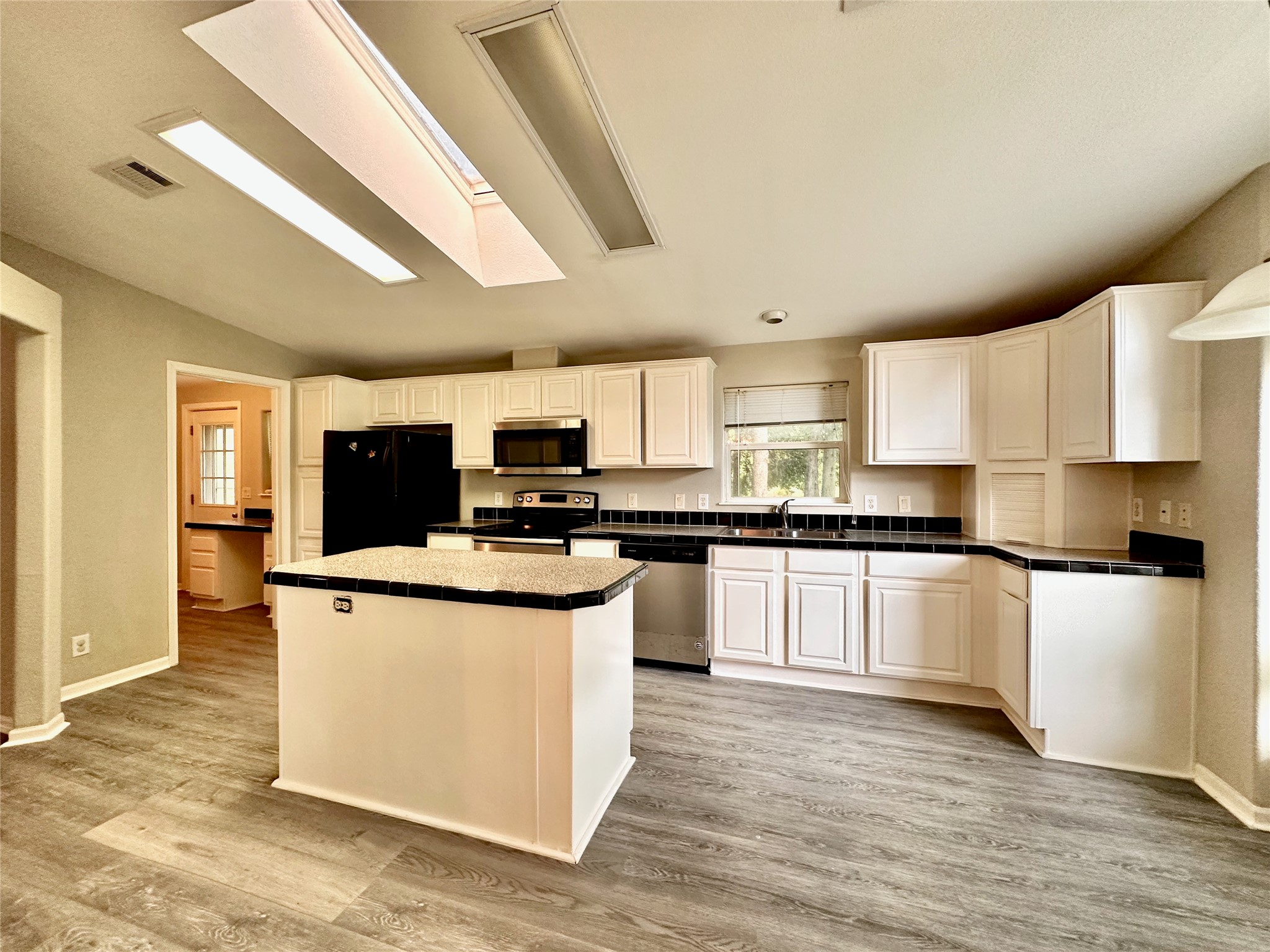 202 Main Street Fresno, TX 77545 - Photo 13 of 26 a kitchen with stainless steel appliances a stove top oven a sink a refrigerator white cabinets and wooden floor