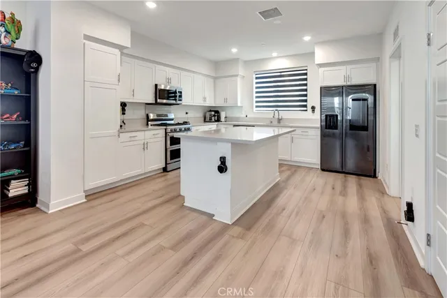 a kitchen with stainless steel appliances granite countertop a stove top oven a sink dishwasher and a refrigerator with wooden floor