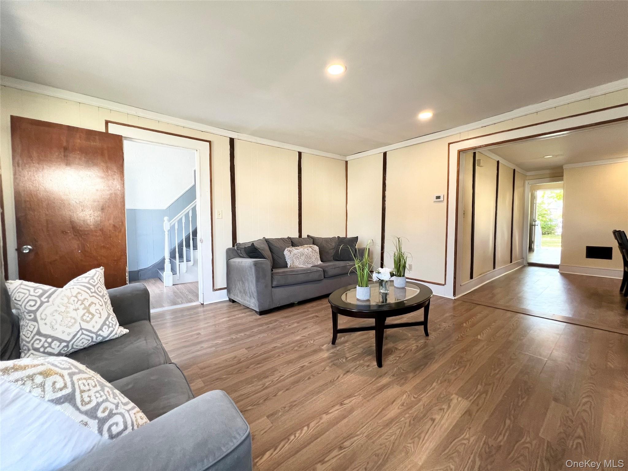 Living area featuring stairs, crown molding, wood finished floors, and recessed lighting