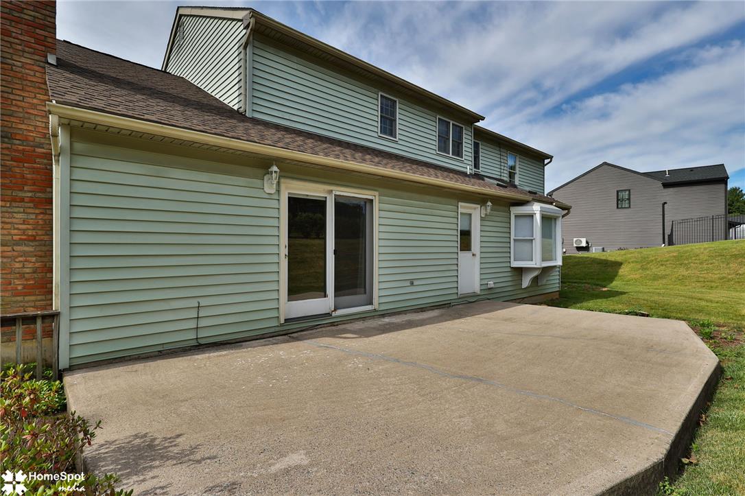 4059 Wedgewood Road Allentown, PA 18104 - Photo 62 of 72 A spacious patio expands outdoor living from the home's rear entrance, set against a backdrop of natural green space.
