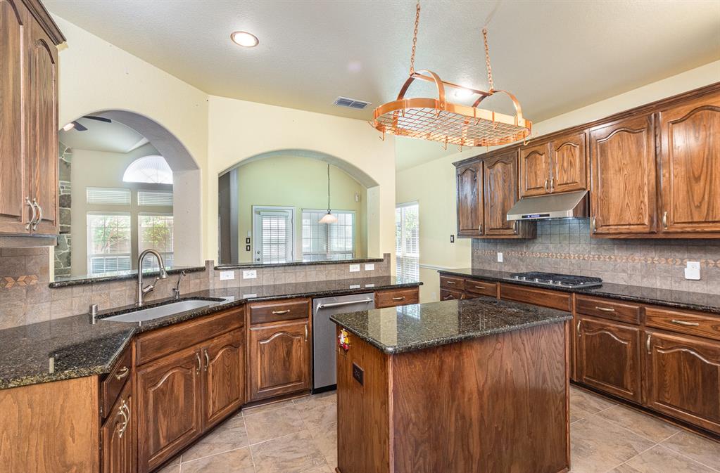 1325 Bateman Lane Celina, TX 75009 - Photo 10 of 39 a kitchen with stainless steel appliances granite countertop a sink stove cabinets and wooden floor