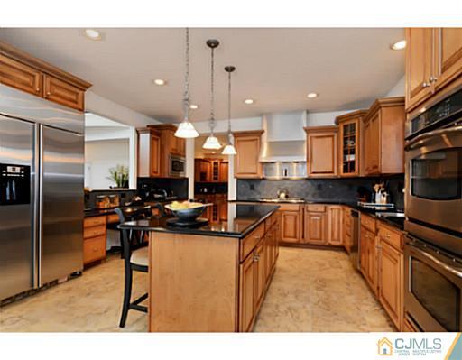 4 Rustic Court Monroe Township, NJ 08831 - Photo 8 of 25 a kitchen with stainless steel appliances kitchen island granite countertop a sink refrigerator and cabinets