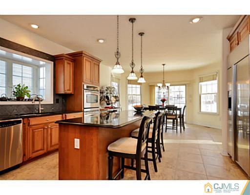4 Rustic Court Monroe Township, NJ 08831 - Photo 9 of 25 a dining hall with stainless steel appliances kitchen island granite countertop a table chairs and a living room view