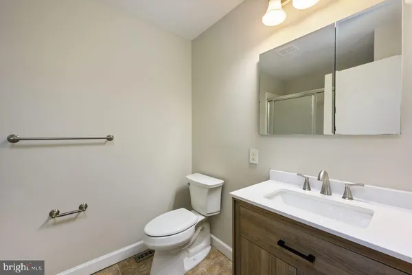 a bathroom with a granite countertop toilet sink and mirror