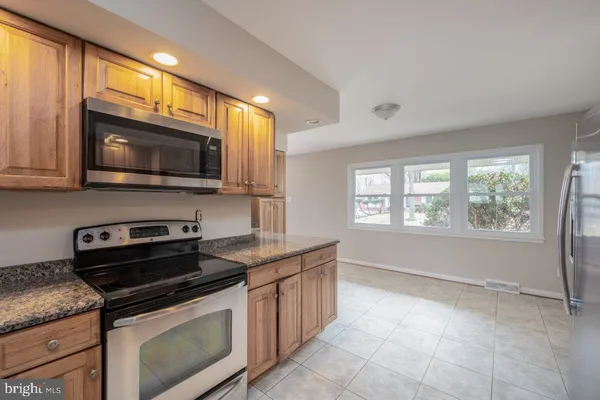 a kitchen with granite countertop a stove top oven microwave and cabinets