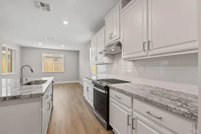 a kitchen with granite countertop a sink stainless steel appliances and cabinets