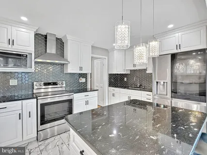 a kitchen with stainless steel appliances granite countertop a sink a stove and a wooden floors