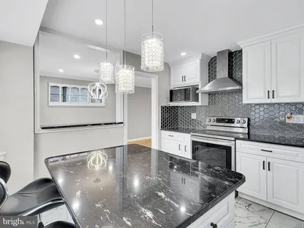 a kitchen with granite countertop a stove a sink and a refrigerator