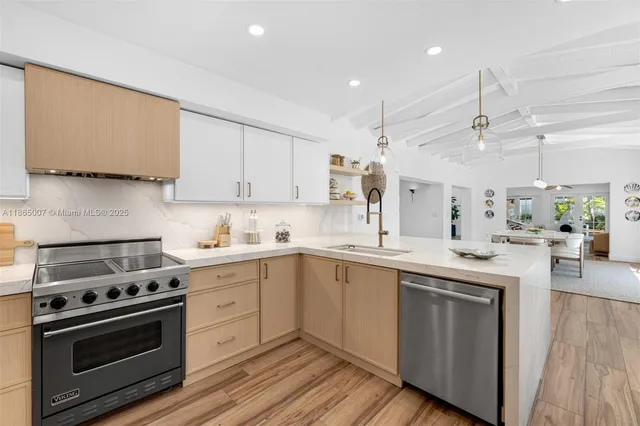 a kitchen with stainless steel appliances kitchen island granite countertop a dining table chairs and a refrigerator