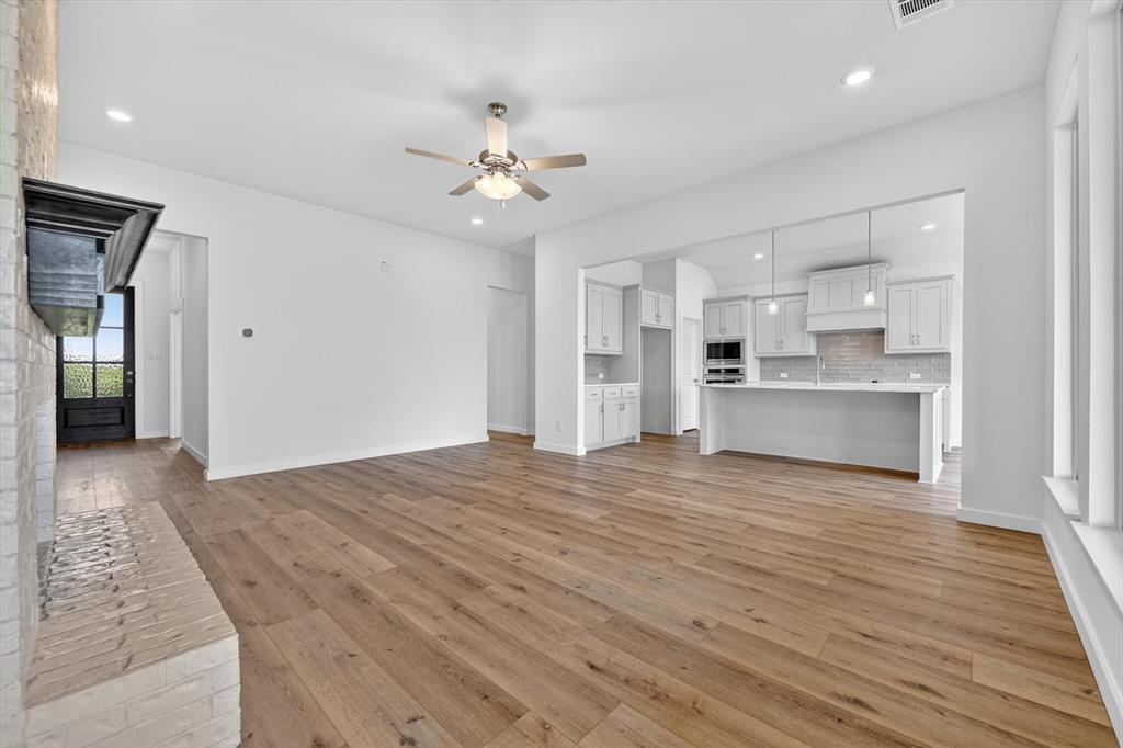 416 McAlpine Drive Springtown, TX 76082 - Photo 11 of 40 Spacious open-concept living area featuring wood-finish flooring, a white brick fireplace with a dark mantel, and recessed lighting