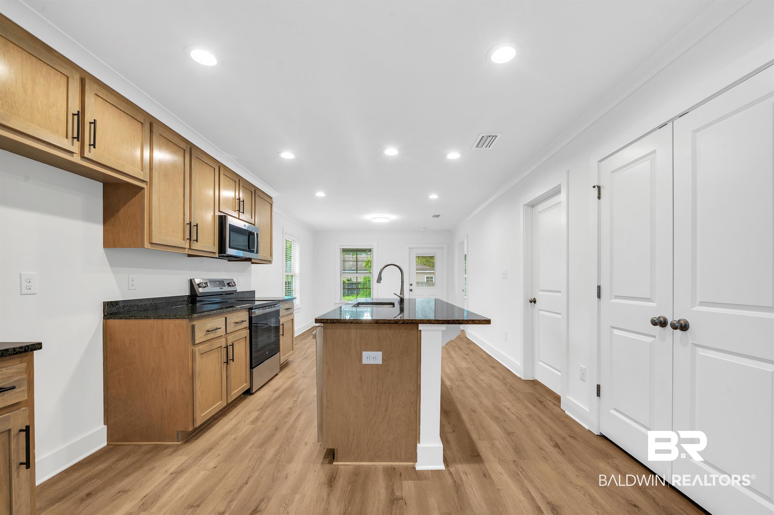 22045 8th Street Silverhill, AL 36576 - Photo 11 of 39 Kitchen featuring appliances with stainless steel finishes, light wood-style flooring, dark stone countertops, baseboards, and a sink