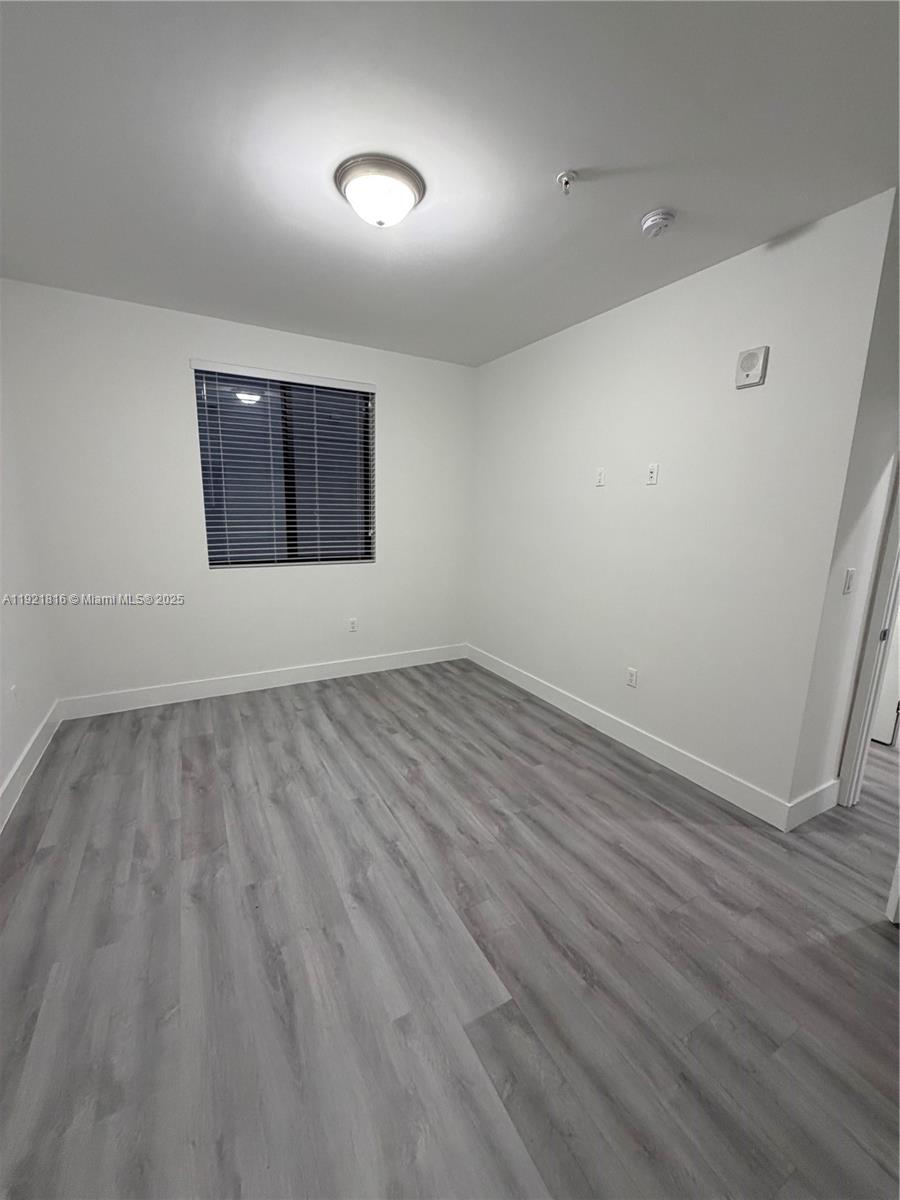 859 East 24th Street, Unit 402 Hialeah, FL 33013 - Photo 10 of 22 an empty room with wooden floor and windows