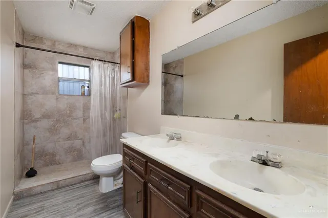 a bathroom with a granite countertop sink a toilet and a shower