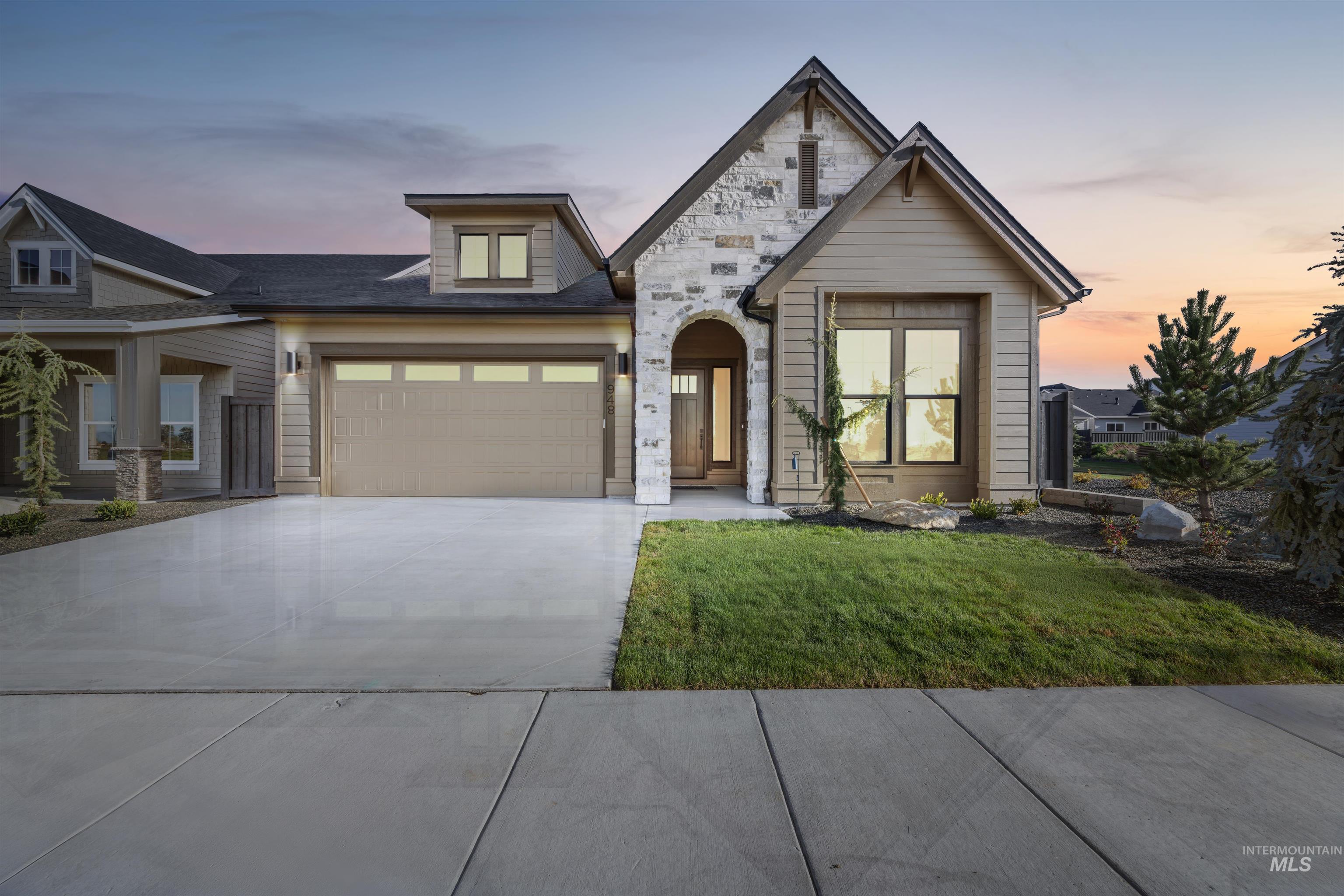 948 East Escalation Street Meridian, ID 83642 - Photo 1 of 44 View of front facade featuring concrete driveway, stone siding, a yard, and an attached garage